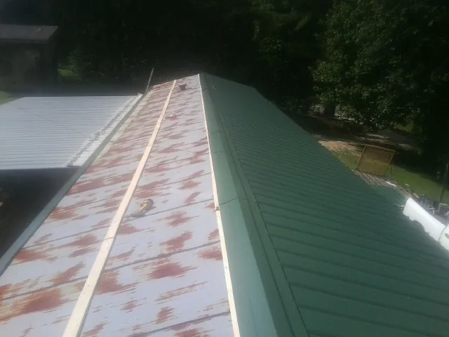 Old rusted panels beside newly installed green metal roofing — Wind Damage Roof Repair by Roofing Brothers in Glencoe