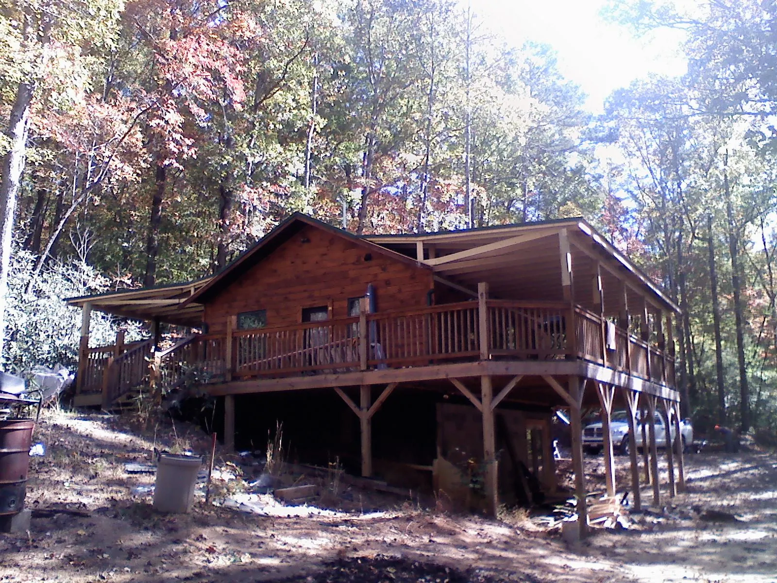 Log cabin with a wraparound porch and metal roof in the fall in Glencoe