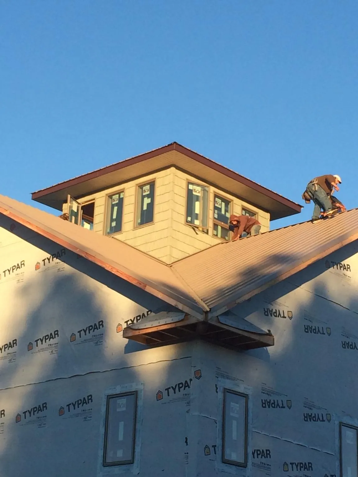 Roofers working around a rooftop cupola on a new metal roof at sunset — Roof Waterproofing in Glencoe by Roofing Brothers